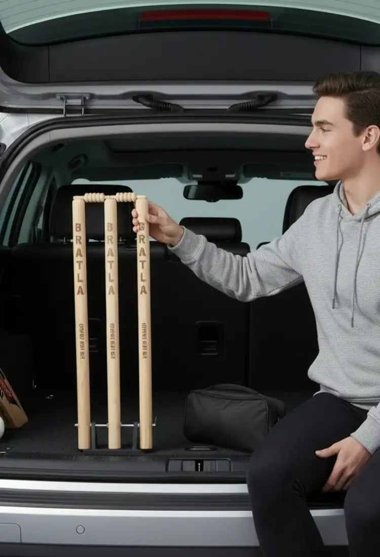 Set of four light-colored wooden cricket stumps with ’bratla’ engraved vertically on each, designed for outdoor play.
